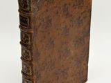 an old book sitting on top of a white table next to a white wall