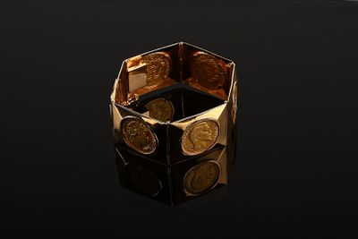 an image of a gold ring with coins on a black surface