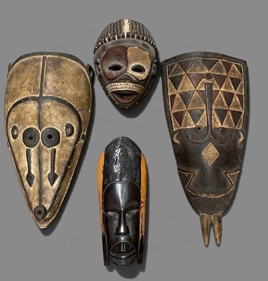 four african masks on a gray surface with a gray background