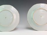 two white plates with gold rims are sitting on a white surface