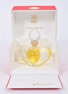 une image représentant un flacon de parfum dans une boîte, posé sur une surface blanche