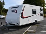 un petit camping-car blanc garé sur un parking