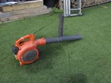 un souffleur orange posé sur l'herbe dans le jardin