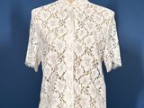 a white lace shirt on a mannequin stand against a blue wall