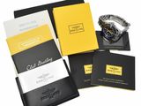 a black and yellow box containing a watch, a notebook, and a watch