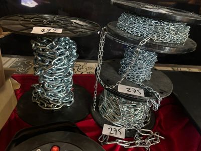 deux bobines de chaîne et une bobine de fil métallique posées sur une table