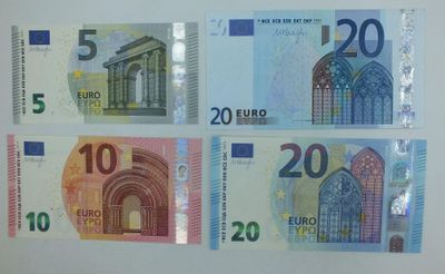 quatre billets de banque différents, de formes et de couleurs variées, sur un fond blanc