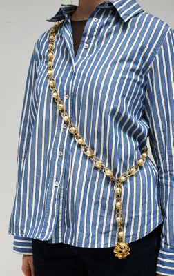 une photo d'une femme portant un t-shirt rayé bleu et blanc et un collier à chaîne dorée