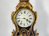 a gold clock that is sitting on a white surface
