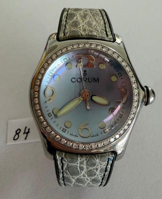 the watch is silver and has a brown leather band