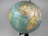 a blue and yellow globe on a stand on a gray background