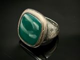 un gros plan d'une bague ornée d'une pierre verte sur un fond noir