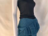 Le mannequin porte un haut noir et une jupe bleue.