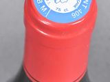 a close up of a bottle of wine with a red cap