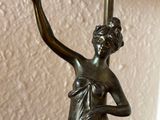 a statue of a woman holding a lamp on a table