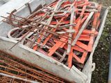un tas de barres de fer rouillées posées par terre, à côté d'un autre tas de barres de fer rouillées