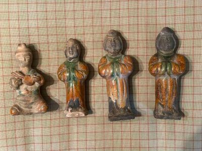 Trois figurines représentant des personnes d'origine asiatique sont assises sur une nappe à carreaux.