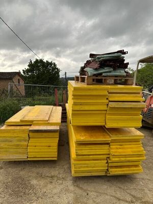plusieurs piles de bois jaune empilées les unes sur les autres devant un camion