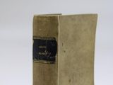 an old book sitting on top of a white table next to a white wall