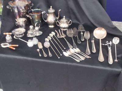 a lot of silverware on a table with a black cloth