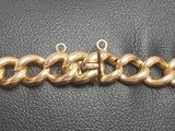 a close up of a gold chain bracelet on a black leather surface