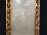 un miroir à cadre doré posé sur une table près d'un mur noir