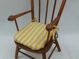 une image représentant une chaise en bois avec un coussin d'assise rayé jaune et blanc