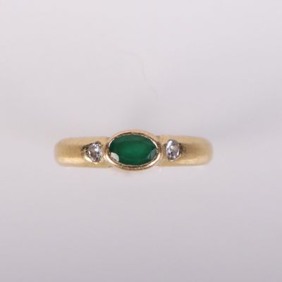 gros plan d'une bague en or avec une pierre verte