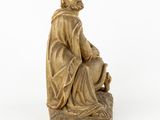 a statue of a man sitting on top of a rock