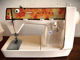 a white sewing machine sitting on a table next to a box