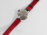 a close up of a watch on a white surface with a red strap