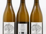 trois bouteilles de vin posées les unes à côté des autres sur une surface blanche