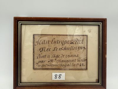 une vieille photo encadrée représentant une citation, accrochée au mur