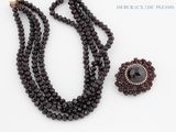 un gros plan d'un collier et d'une broche posés sur une surface blanche