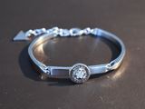 silver bracelet with a diamond on it sitting on a table