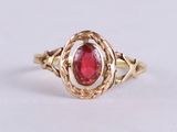 a close up of a gold ring with a red stone in the center
