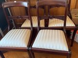 quatre chaises en bois avec des assises rembourrées dans une pièce