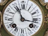 a green and gold clock with roman numerals on it