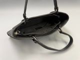 black leather handbag on white surface with strap and handle