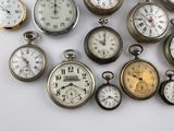 many different types of pocket watches displayed on a white surface