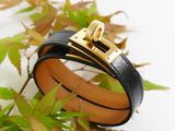 black leather bracelet with a gold buckle on a white surface
