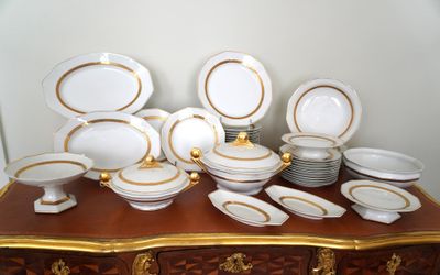 une multitude d'assiettes et de bols blancs et dorés posés sur une table