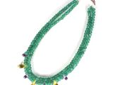 a close up of a green beaded necklace on a white surface