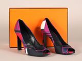 une paire d'escarpins noirs et roses, avec une boîte en arrière-plan