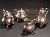 three silver teapots and a sugar shaker on a table