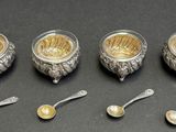 four silver teapots and spoons with spoons on a table
