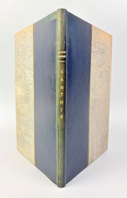 un vieux livre à la couverture bleue posé sur une table blanche