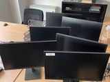 quatre écrans d'ordinateur posés sur un bureau dans un bureau