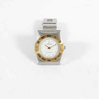 une montre-bracelet argentée et dorée posée sur une surface blanche