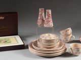 une table dressée avec des tasses, des soucoupes, des assiettes et une lampe